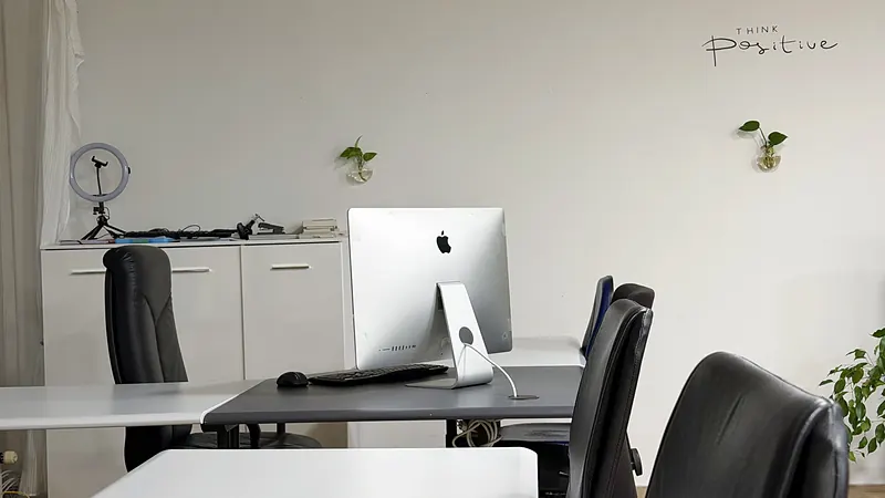 Workstation with iMac and Think positive wall motto at Webzenz